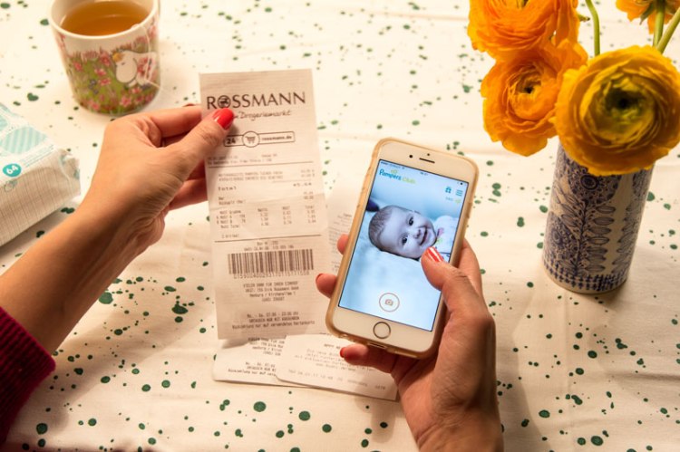 Frau mit Handy testet die neue Pampers-App: Bon und Startseite App