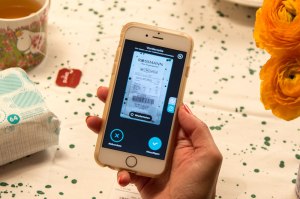 Frau mit Handy testet die neue Pampers-App: Kassenbon scannen