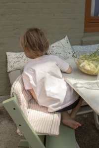 Kind gießt Apfelsaft über Holunderblüten, sitzt dabei auf Tripp Trapp in den neuen Farbe 2017 Moss Green