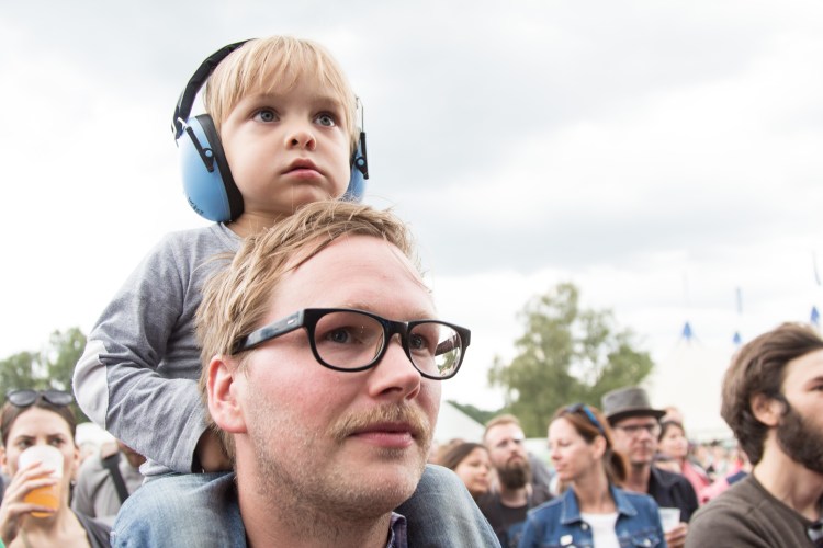 A Summers Tale-Festival mit Kind: Kind mit Gehörschutz auf Papas Schultern