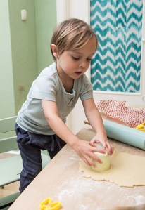 Kind sticht Kekse aus Mürbeteig mit Dinkelmehl
