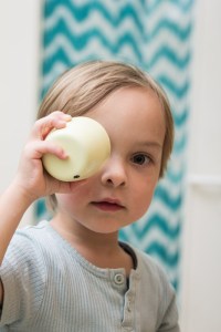 Kind hält Becher vor Auge