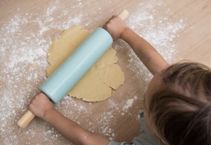 Kind rollt Mürbeteig aus