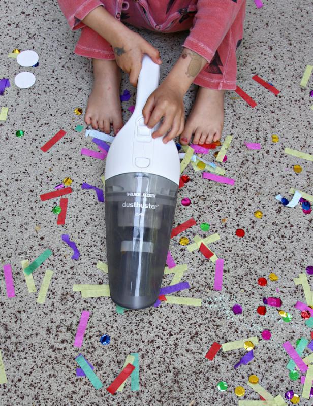 Kind saugt mit dem Handstaubsauger Dustbuster von Black&Decker Konfetti auf