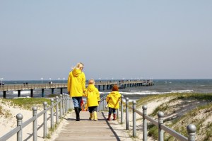 Mutter und Kind mit gelben Regenjacken von Petit Bateau am Strand von Binz auf Rügen