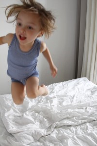 Kind springt auf Bett des Ferienappartments im Dünenhaus in Binz auf Rügen