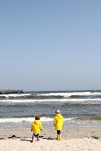 Zwei Kinder mit gelben Regenjacken von Petit Bateau am Strand von Binz auf Rügen