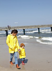 Mutter und Kind mit gelben Regenjacken von Petit Bateau am Strand von Binz auf Rügen