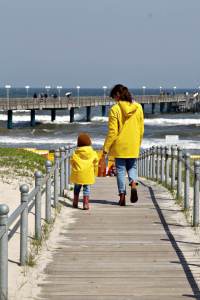 Mutter und Kind mit gelben Regenjacken von Petit Bateau am Strand von Binz auf Rügen