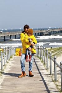 Mutter und Kind mit gelben Regenjacken von Petit Bateau am Strandweg von Binz auf Rügen