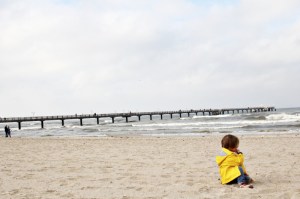 Kind in gelber Regenjacke von Petit Bateau am Strand in Binz auf Rügen