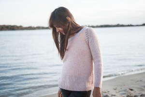 Frau trägt rosanen Pullover aus recycelter Wolle von Another View