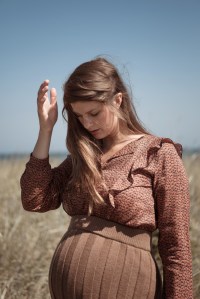 Schwangere Frau trägt Strickrock von Karin Fraidenraij und Bluse mit Rüschen von Lanius