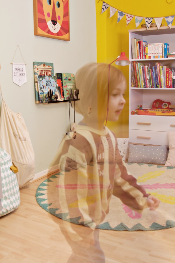 Doppelbelichtung: Kind im bunt eingerichteten Kinderzimmer mit Teppich von Minividuals und Bücherregal von wayfair