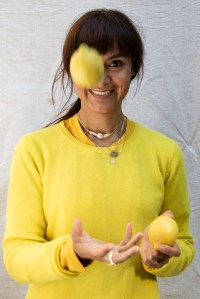 nachhaltiges Kaschmir von Peter Hahn: Frau trägt einen leuchtend gelben Kaschmirpullover und wirft eine Zitrone