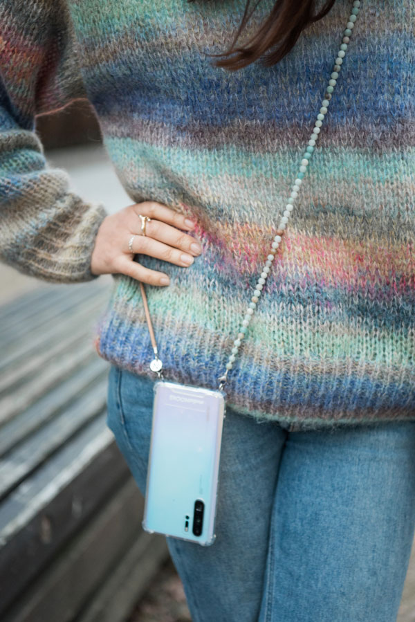 Frau mit buntem Pullover trägt farblich passende Handykette von StudioNooks